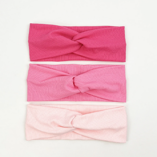 Three pink headbands with twisted designs on a white background