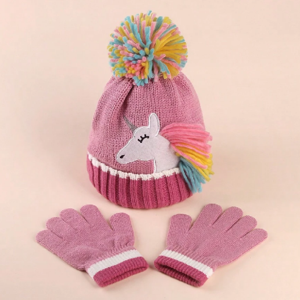 Pink knit hat with unicorn design and colorful pom-pom, paired with pink gloves on a beige background
