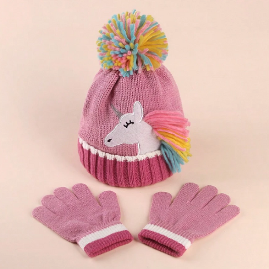 Pink knit hat with unicorn design and colorful pom-pom, paired with pink gloves on a beige background