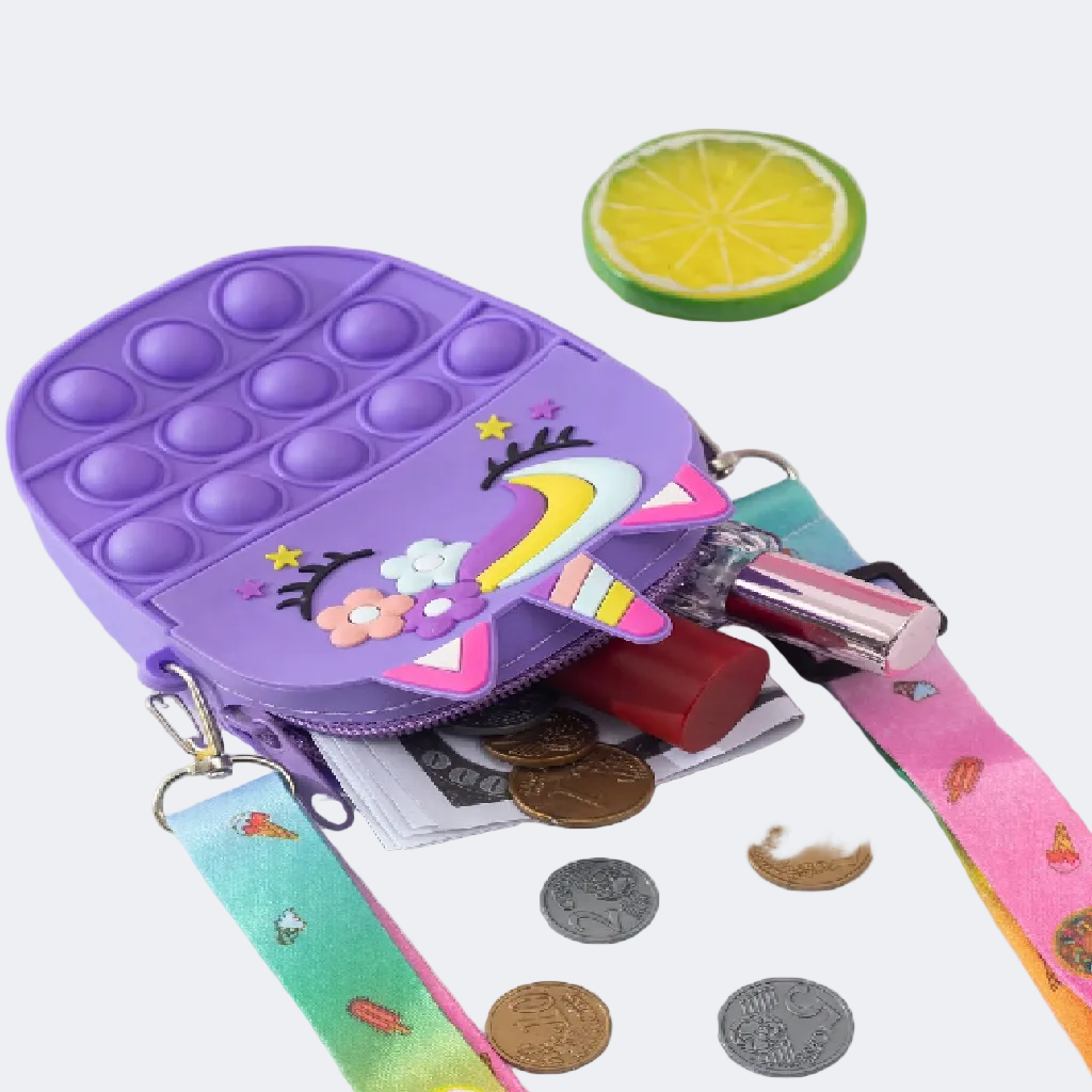 Purple pop-it fidget toy with unicorn design on a white surface with coins and lip balm.