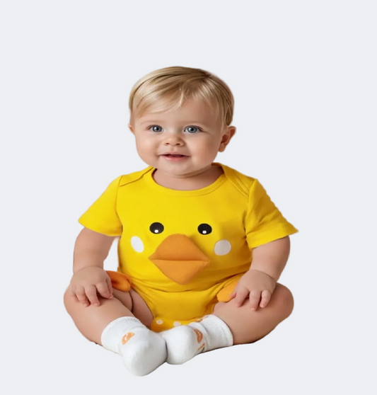 Baby wearing a yellow duck onesie in a decorated room with balloons and toys.