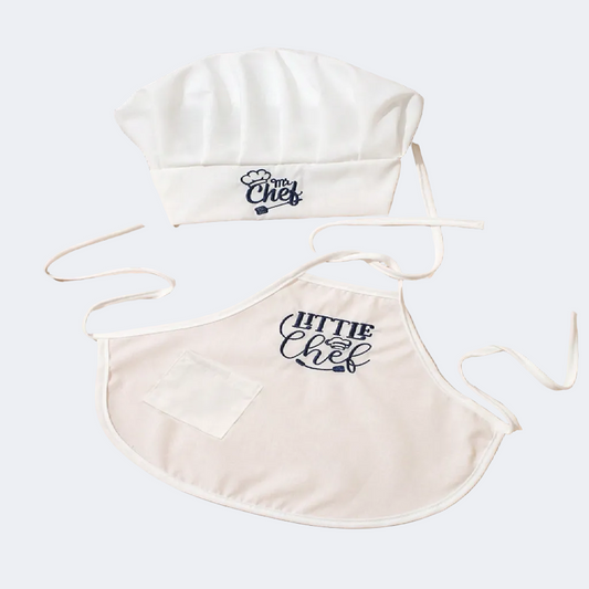 White chef hat and apron with 'Little Chef' text on a beige surface.