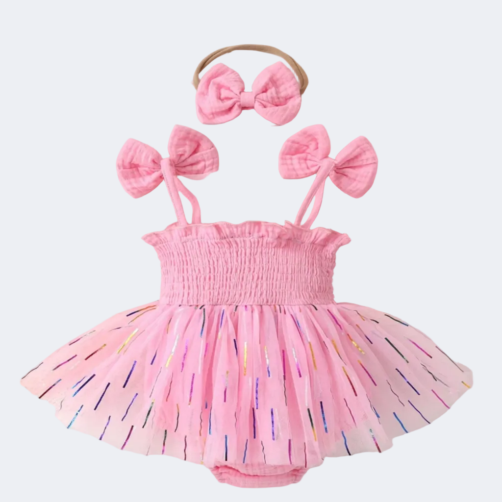 Pink baby dress with colorful sprinkles and matching headbands on a soft background with flowers.