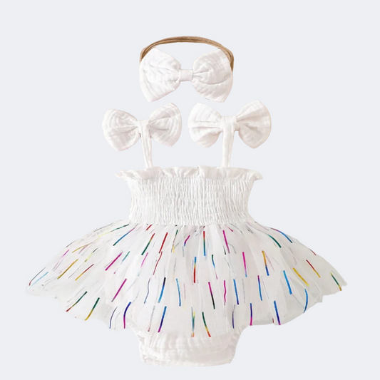 White baby romper with colorful sprinkles and matching headbands on a lace background.