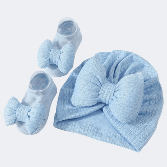 Light blue baby hat and booties set on a light gray background