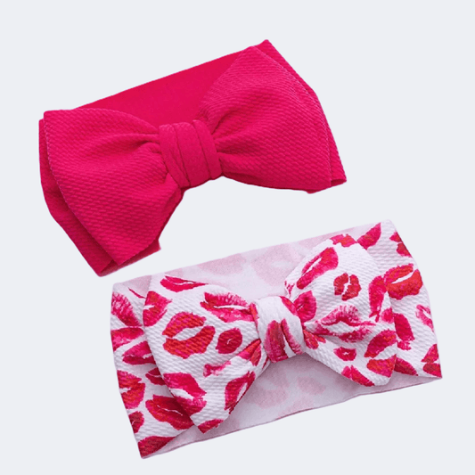 Two headbands with large bows, one pink and one with a red lip print on a white background.