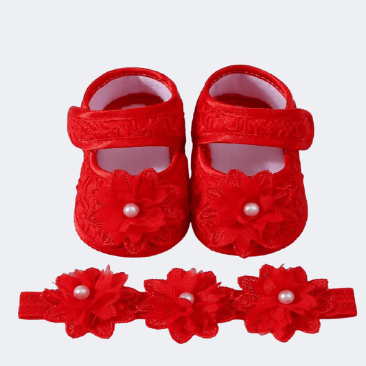 Red baby shoes with floral designs and pearl accents on a white background