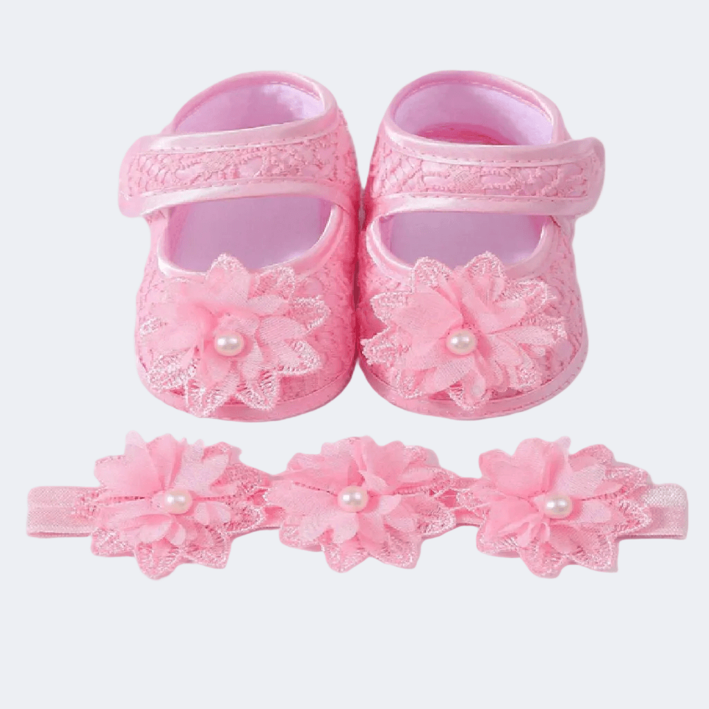 Pink baby shoes with floral designs and headbands on a white background