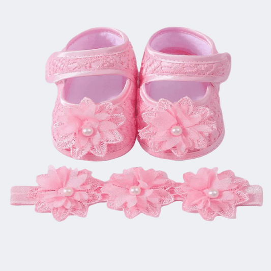 Pink baby shoes with floral designs and headbands on a white background