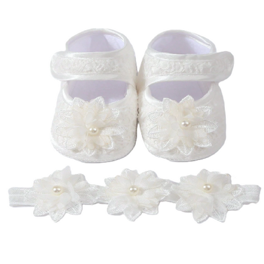 White baby shoes with floral details and a matching headband on a white background
