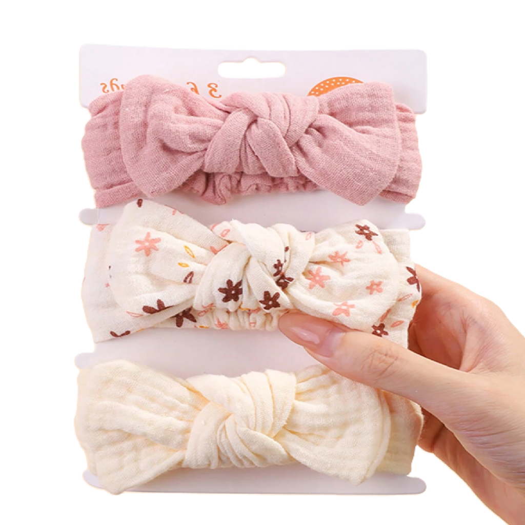 Set of three bow-shaped hair accessories in pink, white with floral pattern, and beige