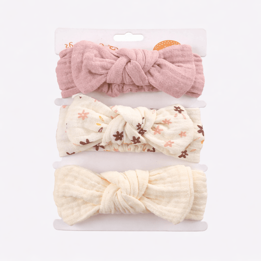 Set of three knotted headbands in pink, white with floral pattern, and yellow on a white background.