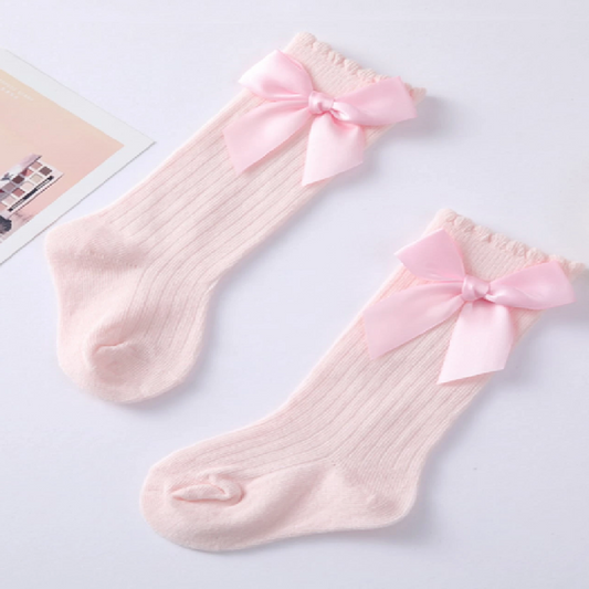 Two pink socks with bow details on a light gray background