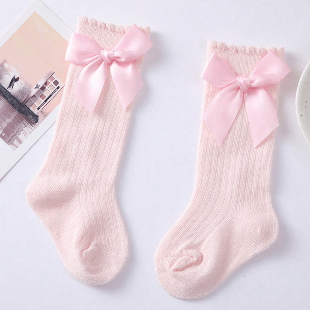 Two pink socks with bow details on a light gray background