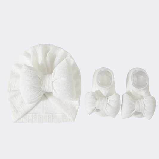 Set of white baby headbands and booties on a light gray background