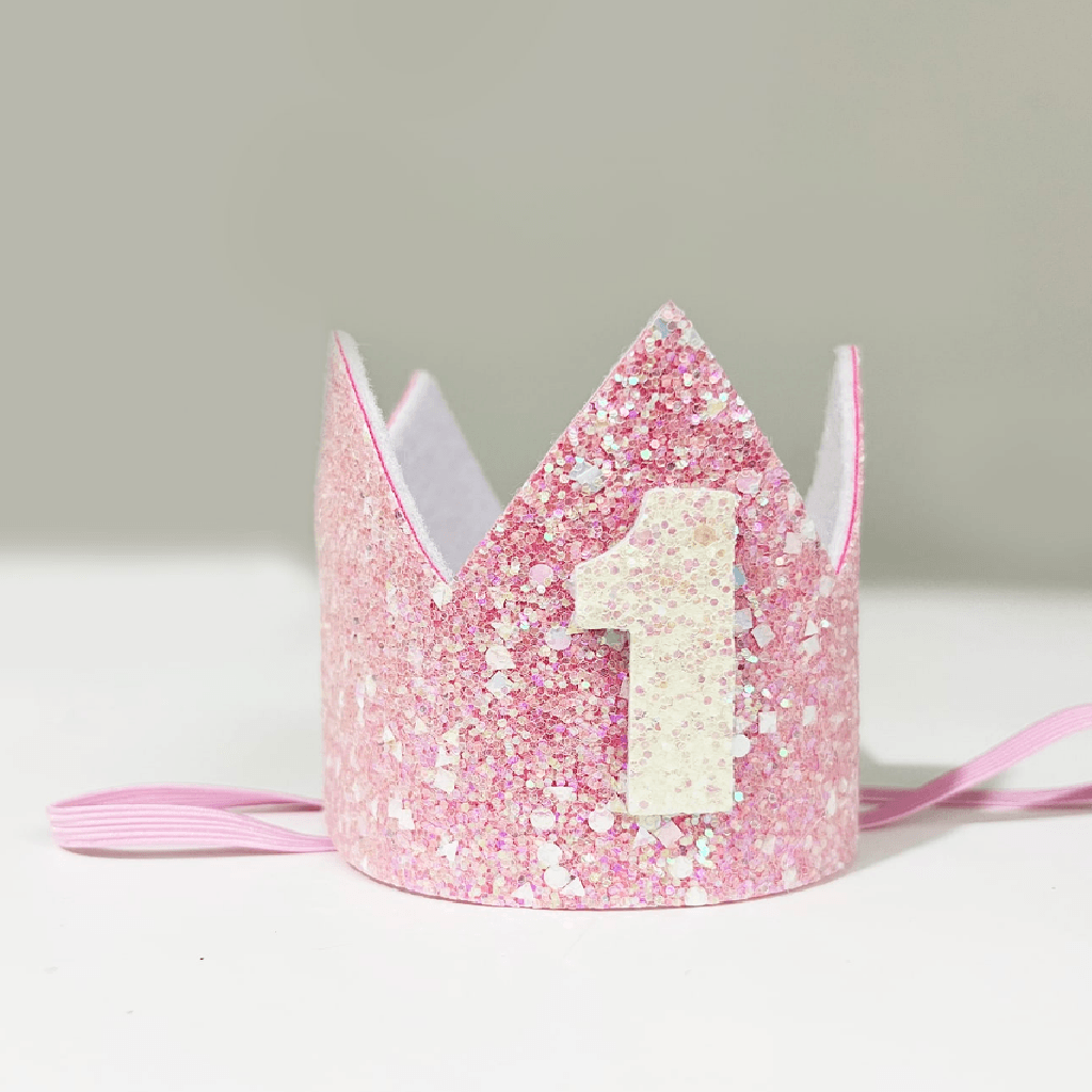 Pink glittery birthday crown with number '1' on a light gray background