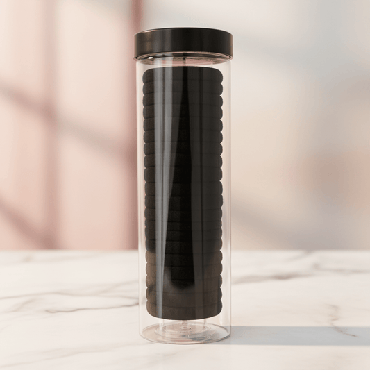 Clear cylindrical container with black textured object inside on a light background