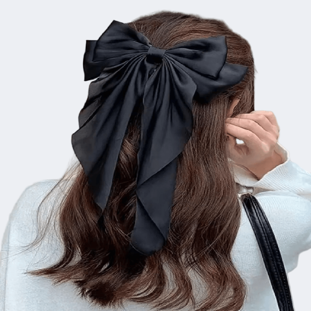 Person wearing a large black bow in their hair against a white background