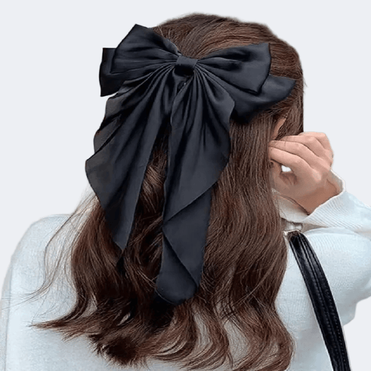 Person wearing a large black bow in their hair against a white background