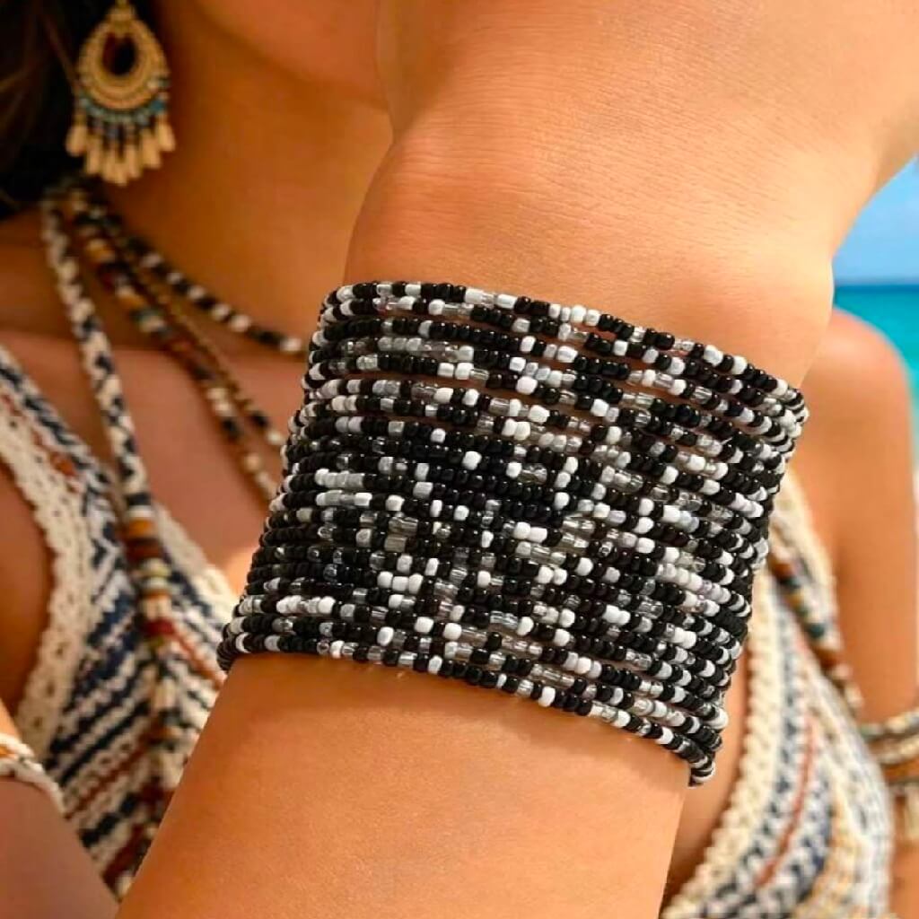Close-up of a person wearing a black and white beaded bracelet with a blurred background.