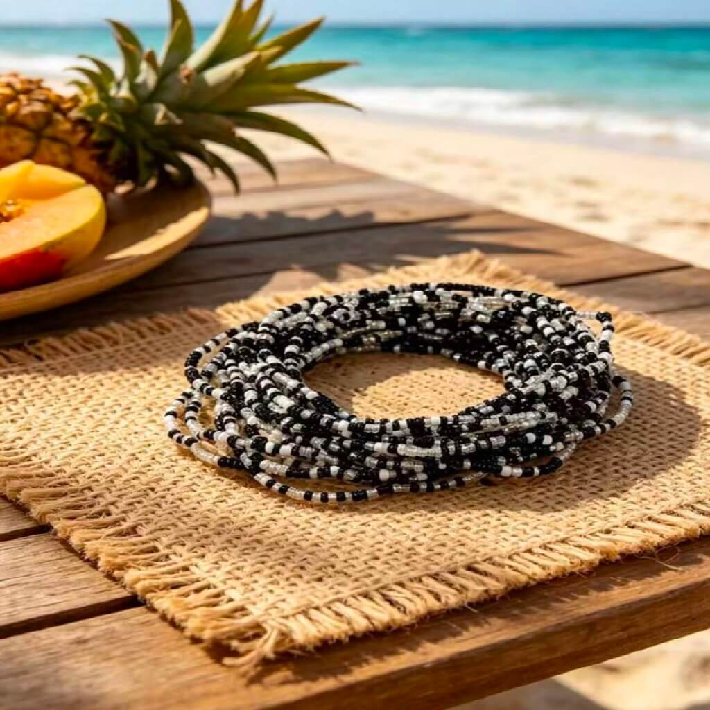 Black and white beaded bracelet on a woven mat with a pineapple and fruit in the background.