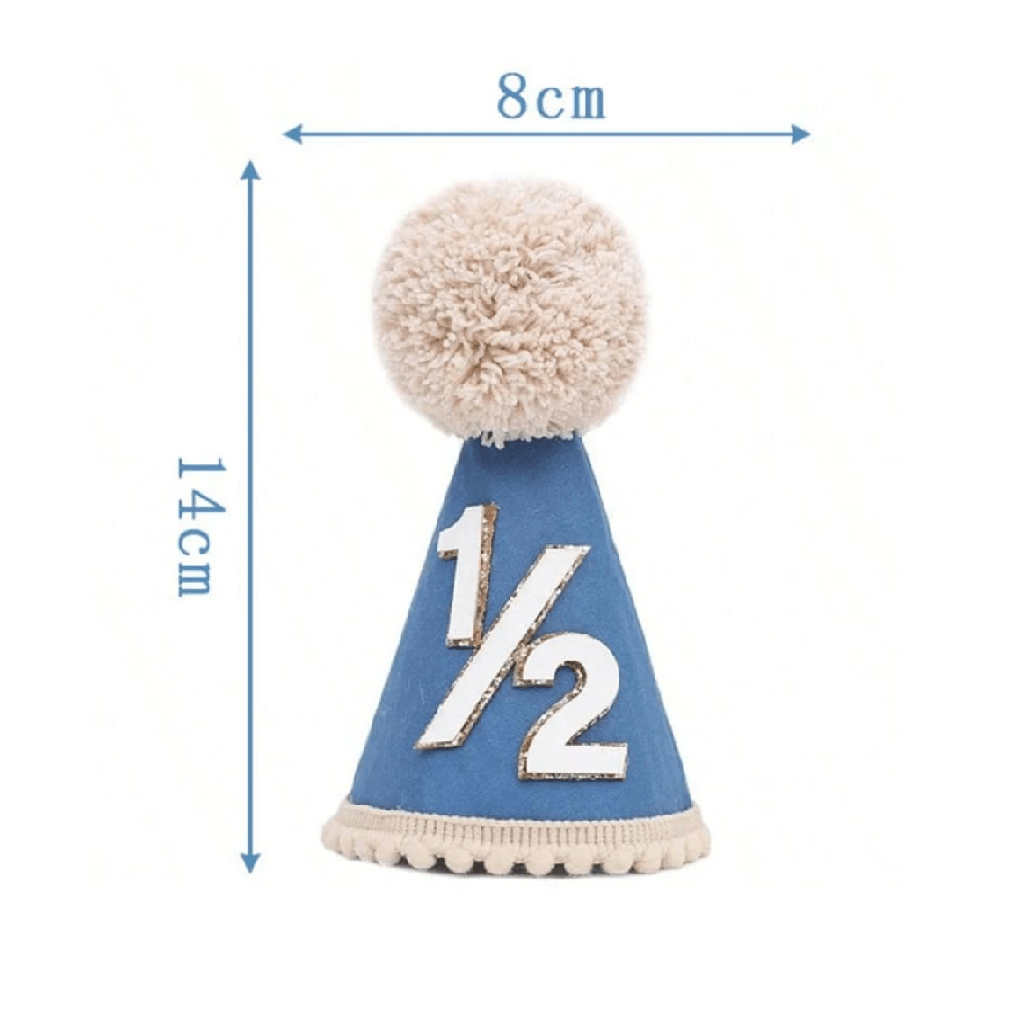 A blue baby half-year party hat with a beige pom-pom on top, white '1/2' text, and a beige ruffled trim, held by a hand against a white background.