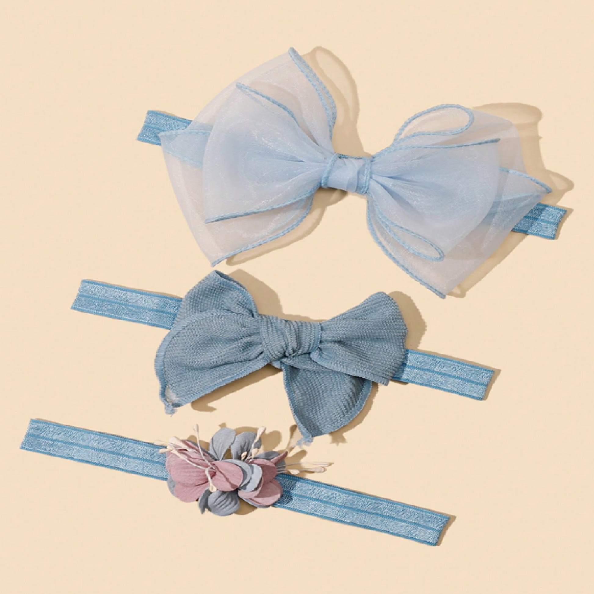 Two blue hair bows with a headband featuring floral details