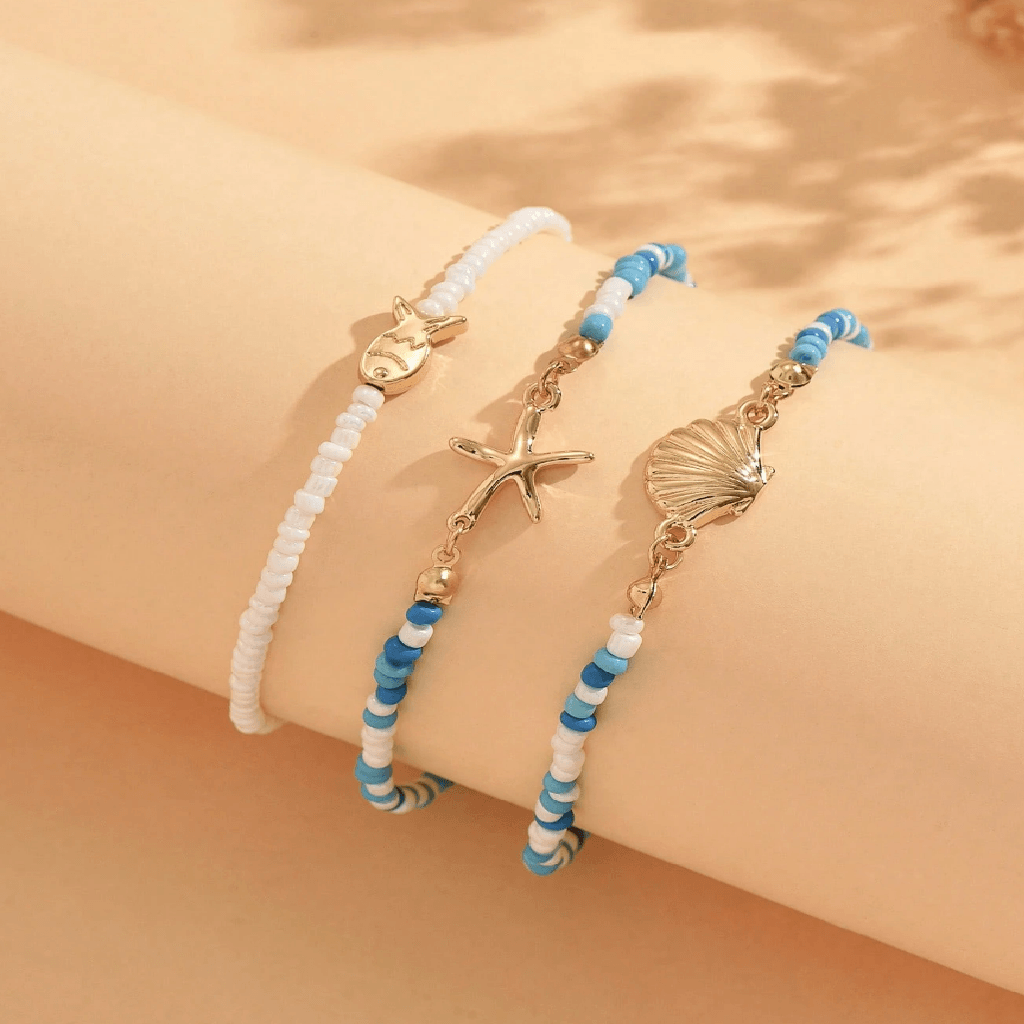 Two beaded bracelets with starfish and shell charms on a beige background