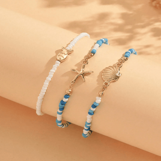 Two beaded bracelets with starfish and shell charms on a beige background