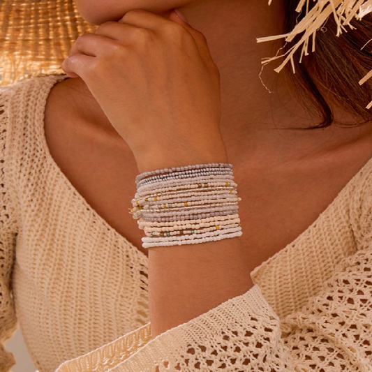 Close-up of a person wearing multiple beaded bracelets on a blurred background