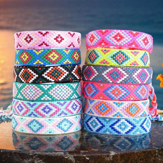 Stacks of colorful patterned bracelets on a reflective surface