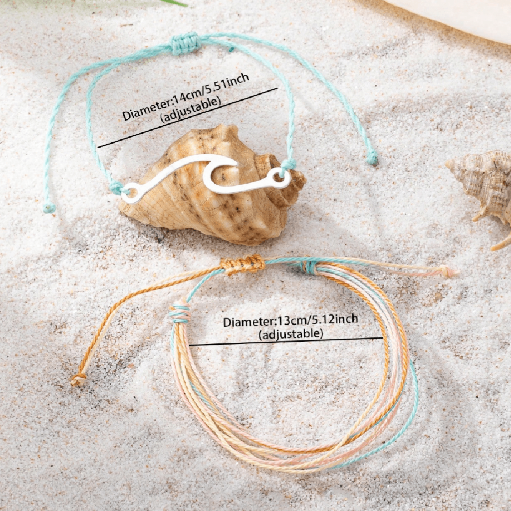 Two bracelets on sand with shells in the background