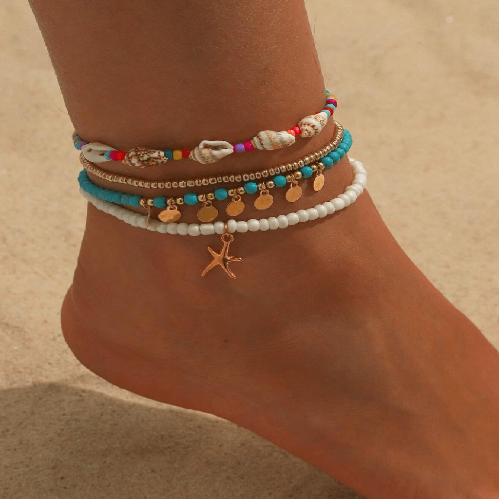Colorful beaded anklets on a foot with a sandy background