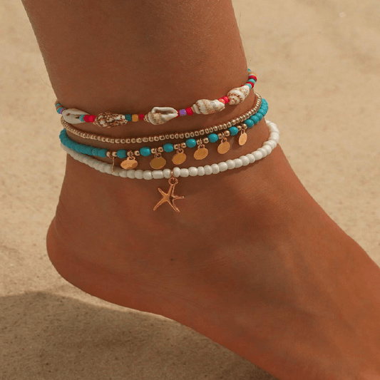 Colorful beaded anklets on a foot with a sandy background