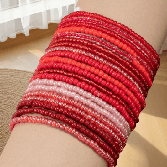 Stack of red beaded bracelets on a person's wrist with a neutral background