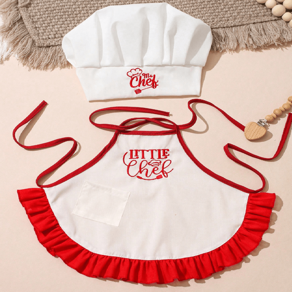 Children's apron with 'Little Chef' text, white chef hat, and wooden beads on a beige background