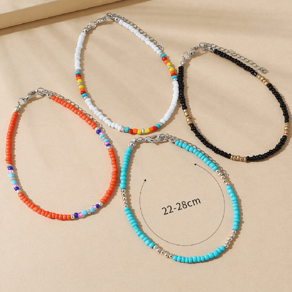 Four beaded necklaces in different colors on a beige surface with a measurement label.