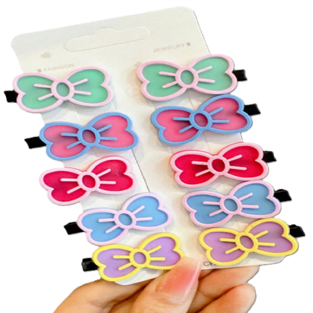 Colorful bow-shaped hair clips on a white card held by a hand.
