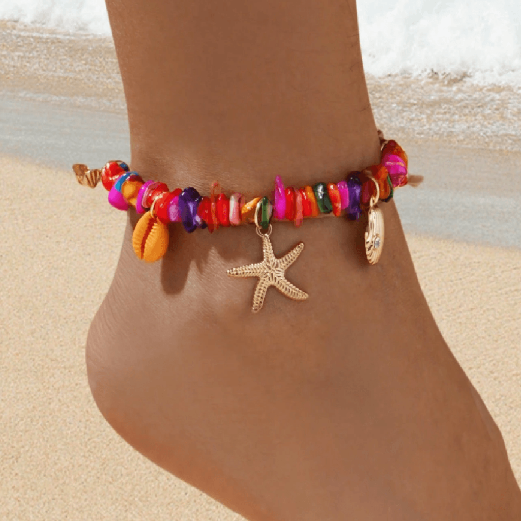 Colorful beaded anklet with starfish charm on a sandy beach