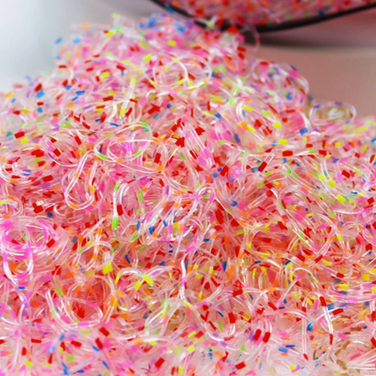 A close-up image of a bundle of disposable hair ties with sunset glow colors, including pink, orange, yellow, and red, with ties visible in the background.