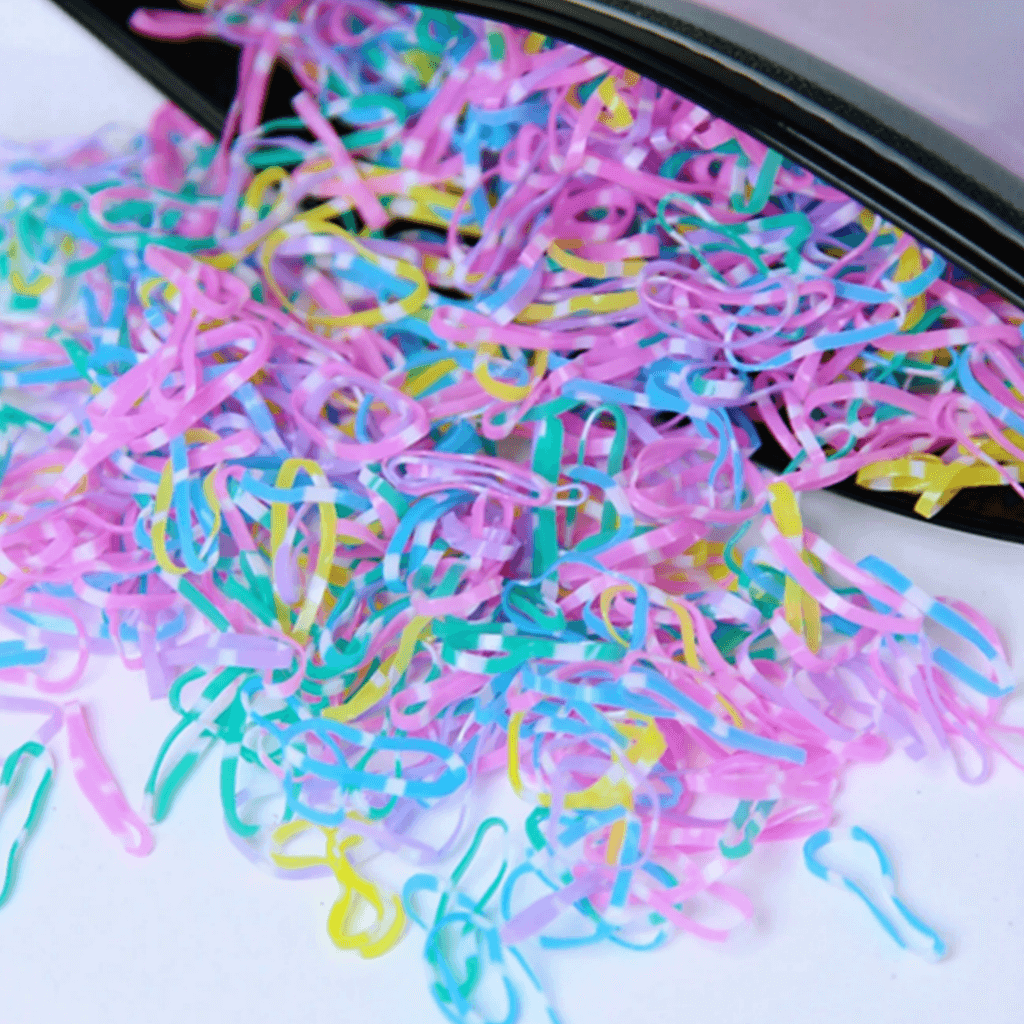 Colorful rubber bands on a white surface with a black container.