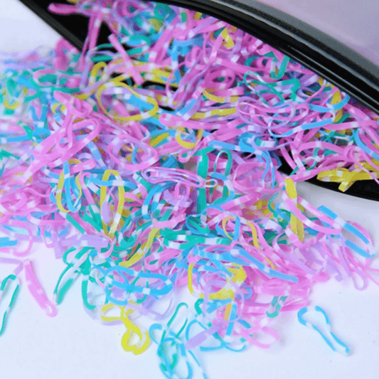Colorful rubber bands on a white surface with a black container.