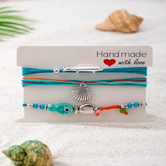 Set of colorful bracelets with charms on a 'Handmade with Love' card, surrounded by shells.