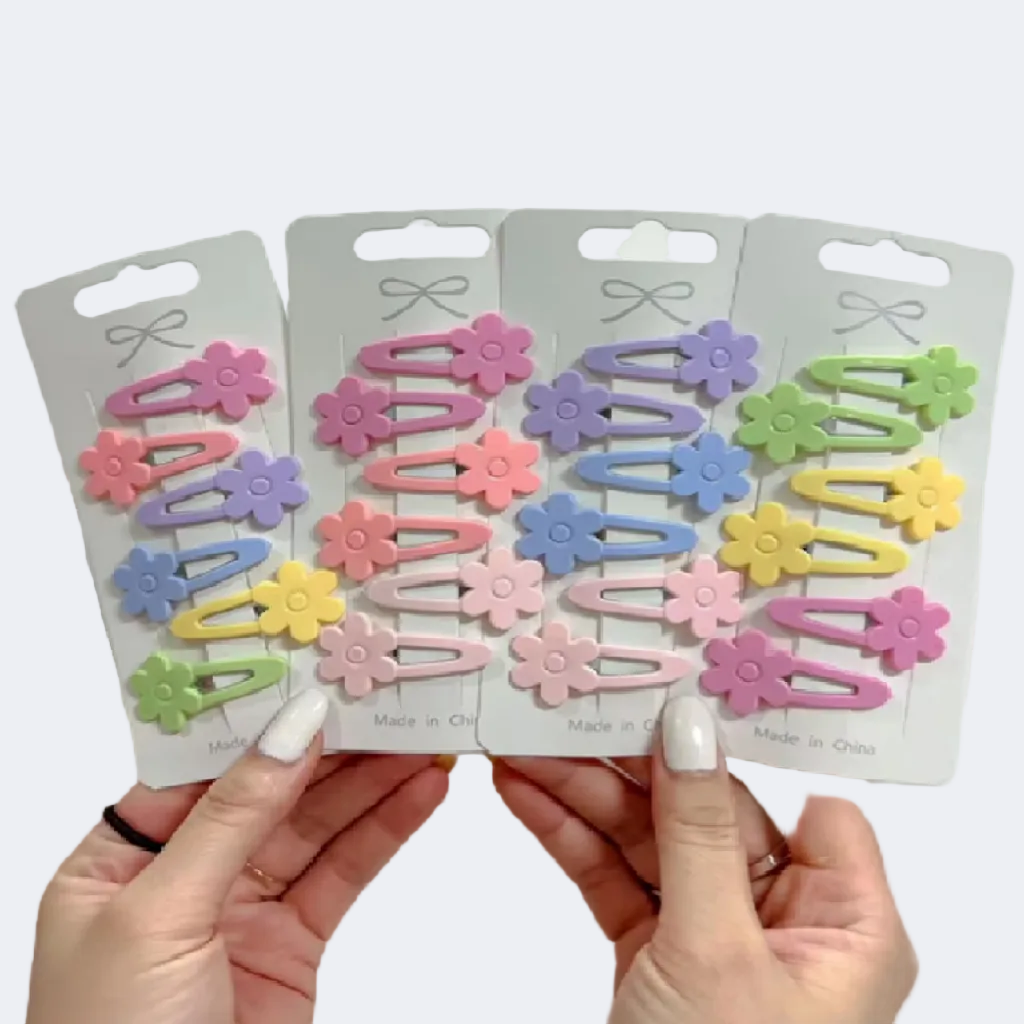 Four packages of colorful flower-shaped hair clips held by hands against a white background