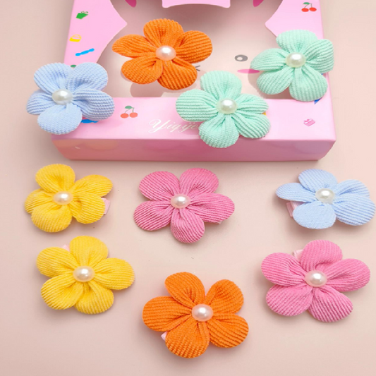 Colorful flower-shaped hair accessories with pearl centers on a pink background