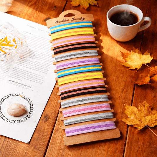 Colorful hair ties on a wooden holder with a cup of coffee and magazine on a wooden surface.