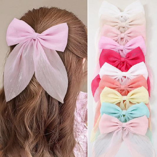 Pastel-colored hair bows on a person's head and stacked together.