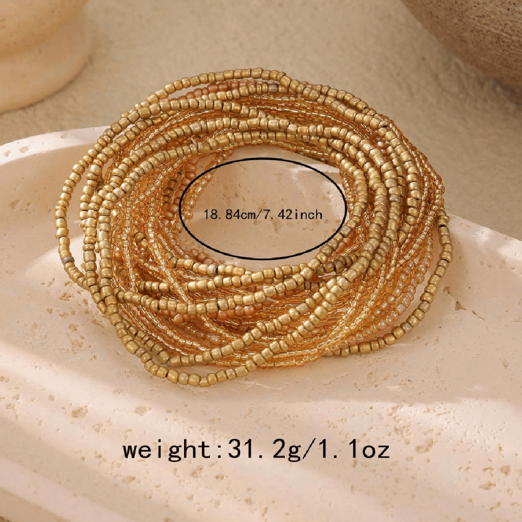 Gold beaded bracelet on a beige stone surface with measurement and weight information.