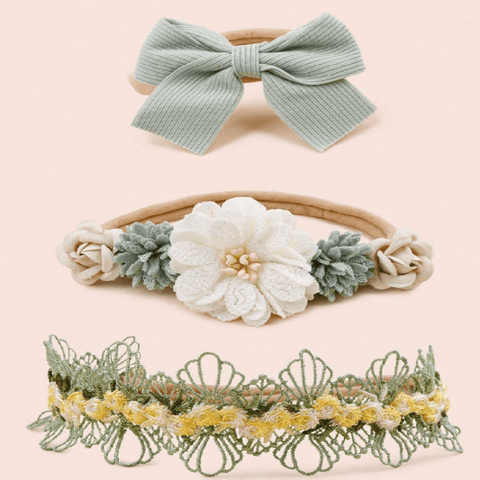 Three decorative headbands with bows and floral designs on a light pink background