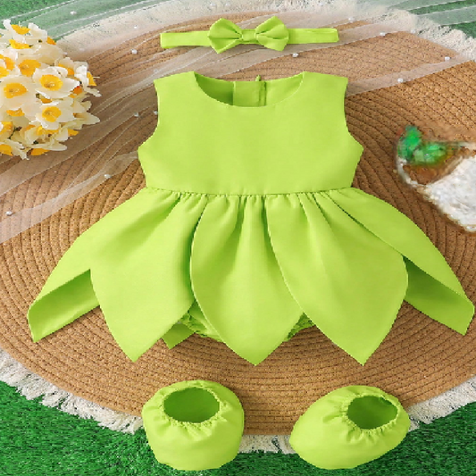 Green baby dress with matching shoes and headband on a textured surface